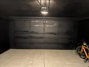 Garage interior with a freshly painted black garage door and ceiling by Jonny Handyman Services in Roy, UT.