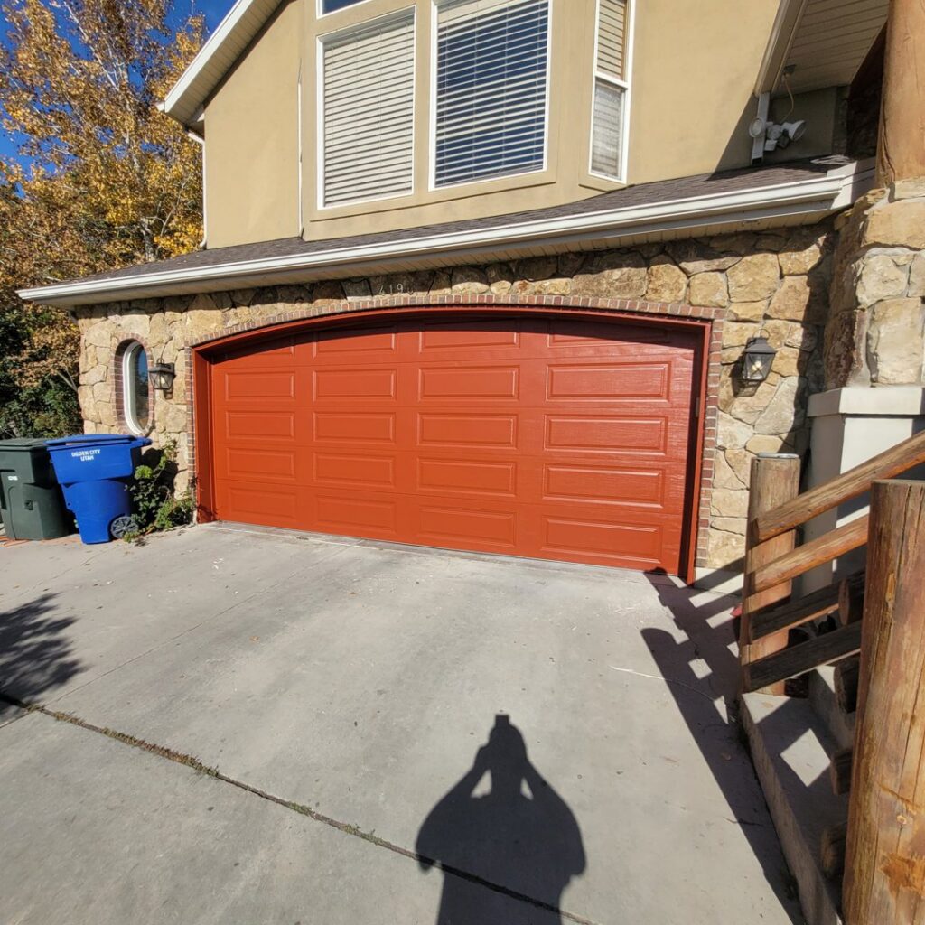 A newly painted orange garage door, a service provided by Joe's Handyman Solutions in Ogden, UT.