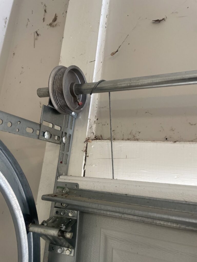 Close-up of a garage door pulley and cable system, showing components repaired by Overhead Door Company of Columbus in Columbus, GA.