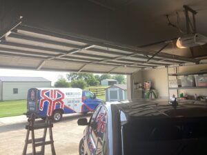 An open garage door with a Riker Garage service van outside, indicating repair or installation work by Riker Home Services in Plano, TX
