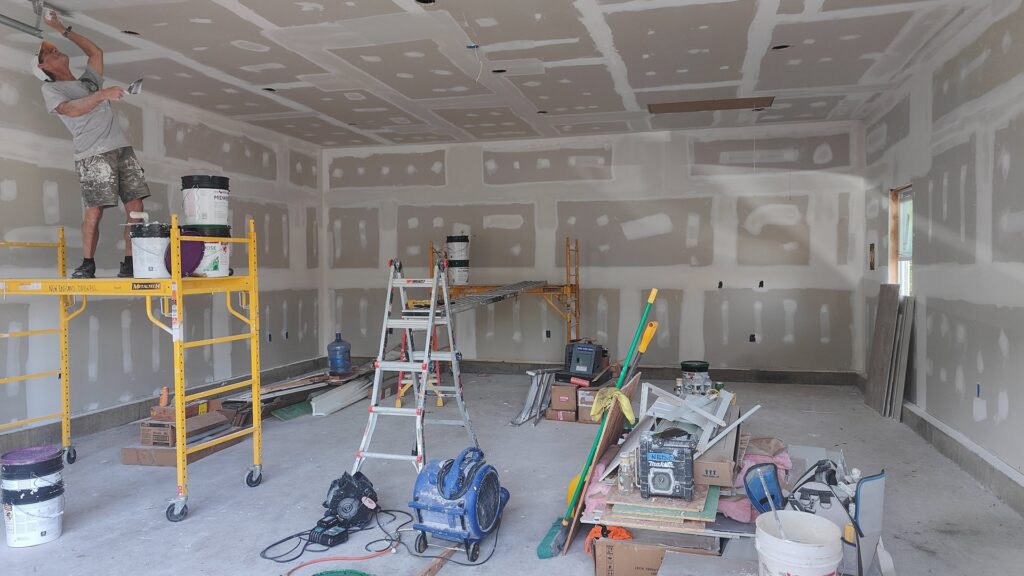 A worker finishing drywall in a large garage or open space, showcasing expert work by NED CO. in Springfield, MA.