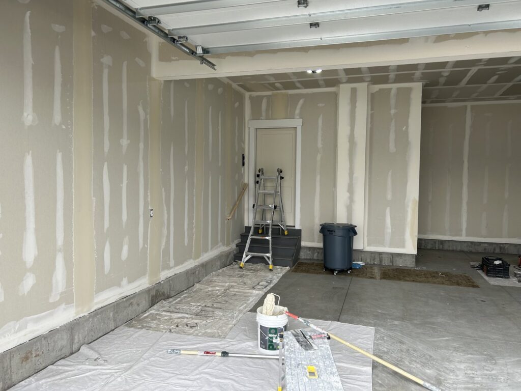 Garage drywall installation and finishing in progress, with tools and supplies, by Rockin & Rollin Handyman Services in North Ogden, UT.