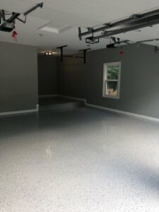 A newly installed speckled grey epoxy floor coating in a clean garage by Quality Painting of Raleigh in Raleigh, NC.