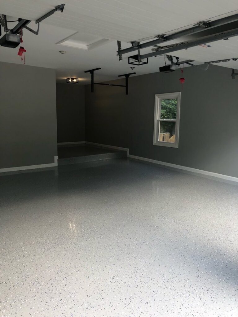 A newly installed speckled grey epoxy floor coating in a clean garage by Quality Painting of Raleigh in Raleigh, NC.