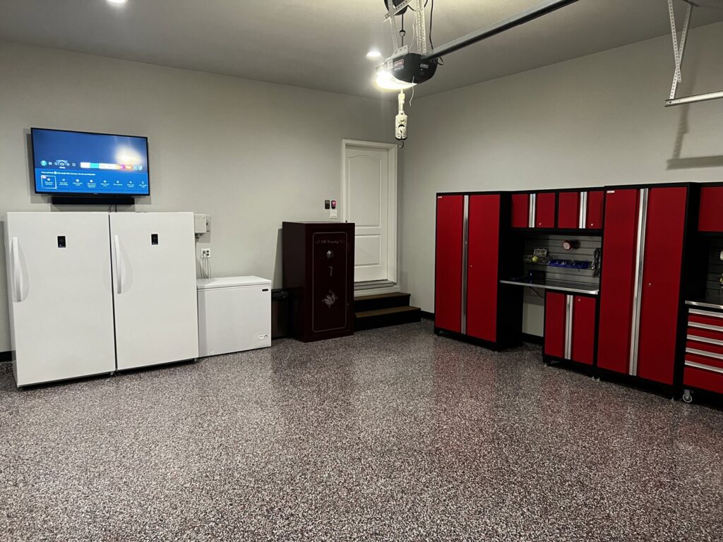 A garage featuring a new epoxy floor and red storage cabinets installed by Greg Unseth Painting & Exteriors in Colorado Springs, CO