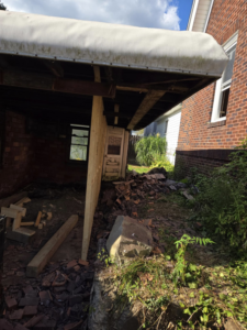 Exterior view of a garage under construction with framing and debris by Crowned Creations in Erie, PA