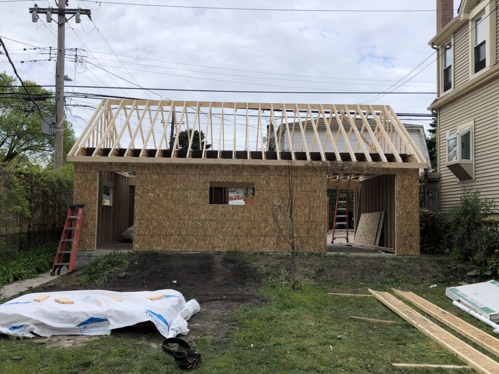 Rear view of a garage under construction with exposed wood framing and roof trusses by A-Windy City Garages & Doors in Chicago, IL.