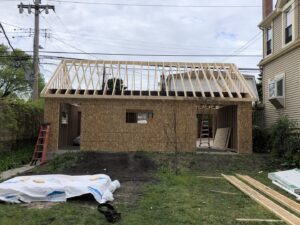 Rear view of a garage under construction with exposed wood framing and roof trusses by A-Windy City Garages & Doors in Chicago, IL.