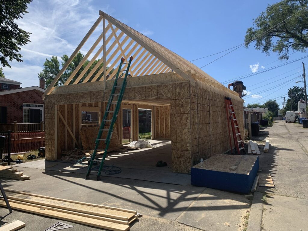 Exterior view of a garage under construction with wall framing and roof trusses installed by A-Windy City Garages & Doors in Chicago, IL.