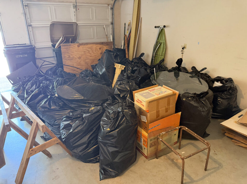 A garage filled with numerous black trash bags and cardboard boxes, ready for junk removal by Junk Out Boyz LLC in Georgetown, TX.