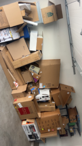 A garage floor completely covered with numerous cardboard boxes, awaiting junk removal by 575 Junk Removal in Clovis, NM.