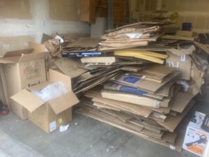 A garage floor covered in a large pile of flattened cardboard boxes ready for removal by Trash It All Hauling And Junk Removal LLC in Fort Collins, CO.