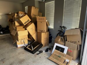 A residential garage filled with numerous cardboard boxes and some broken furniture, ready for Handymen Junk Removal in Houston, TX.