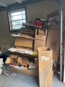 A garage corner overflowing with stacked cardboard boxes, indicating a junk removal job for Jax Junk Squad in Jacksonville, FL.