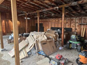 A cluttered garage filled with a large pile of cardboard boxes and other items, ready for junk removal by Missoula Junk Removal, LLC in Missoula, MT.
