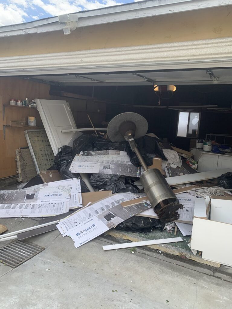 A garage overflowing with construction debris, black trash bags, and various junk, ready for removal by We-Haul Junk Removal in Long Beach, CA