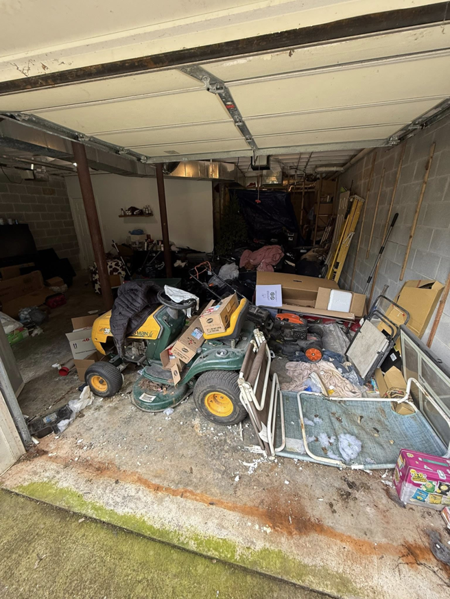 A garage entrance overflowing with junk, including a riding lawnmower, for Marc & Park Junk Removal, LLC in Birmingham, AL.