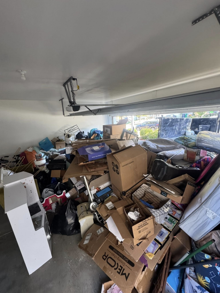 A garage completely filled with a large pile of various junk items before removal by Junkjet in Charlotte, NC.