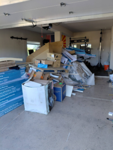 A garage filled with a large pile of cardboard boxes and construction debris, ready for removal by Arizona Junk Removal LLC in Phoenix, AZ