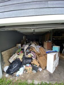 A cluttered garage filled with trash bags, old furniture, and various junk, awaiting removal by EZ Pickups Hawaii LLC in Hilo, HI.
