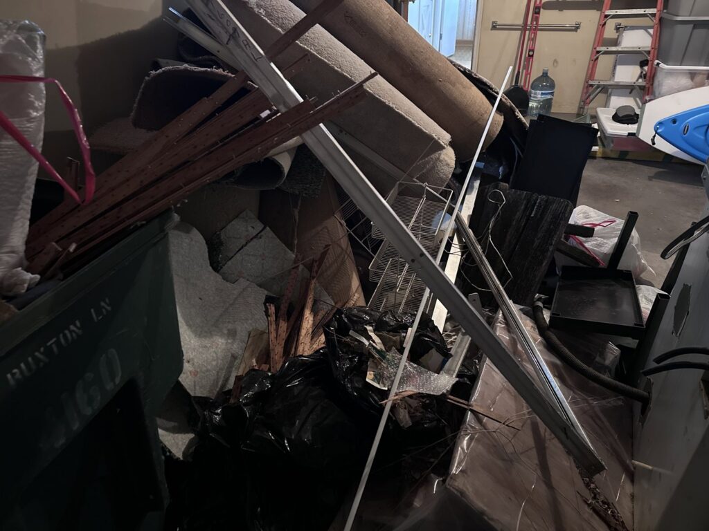 A cluttered garage or basement filled with old carpets, metal, and various junk, ready for removal by 614junkremoval in Columbus, OH.
