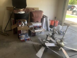 A garage filled with old ceiling fans, boxes, and other items ready for junk removal by Skunky's Junk Removal in Tempe, AZ.