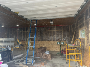 Interior of a garage showing insulation installation and ceiling work in progress by Weathertite Insulation in Oshkosh, WI.