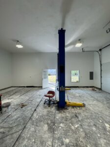 A large garage interior undergoing renovation, with freshly painted walls and floor preparation by Quinonez Painting & Renovations LLC in Providence, RI.