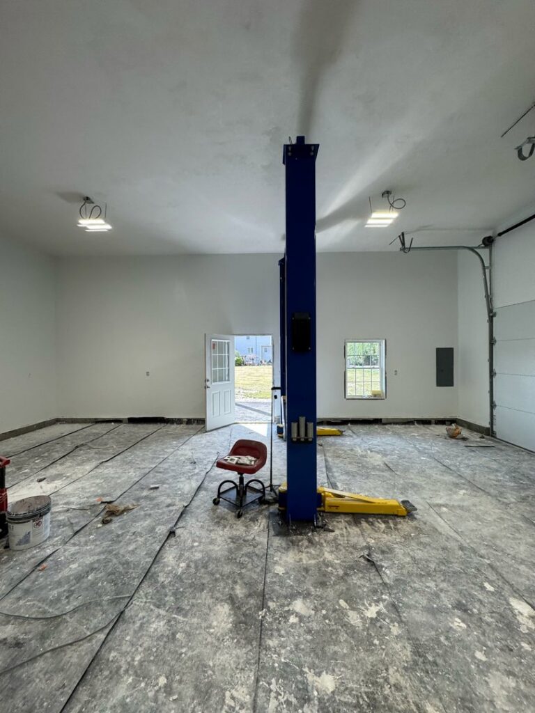 A large garage interior undergoing renovation, with freshly painted walls and floor preparation by Quinonez Painting & Renovations LLC in Providence, RI.