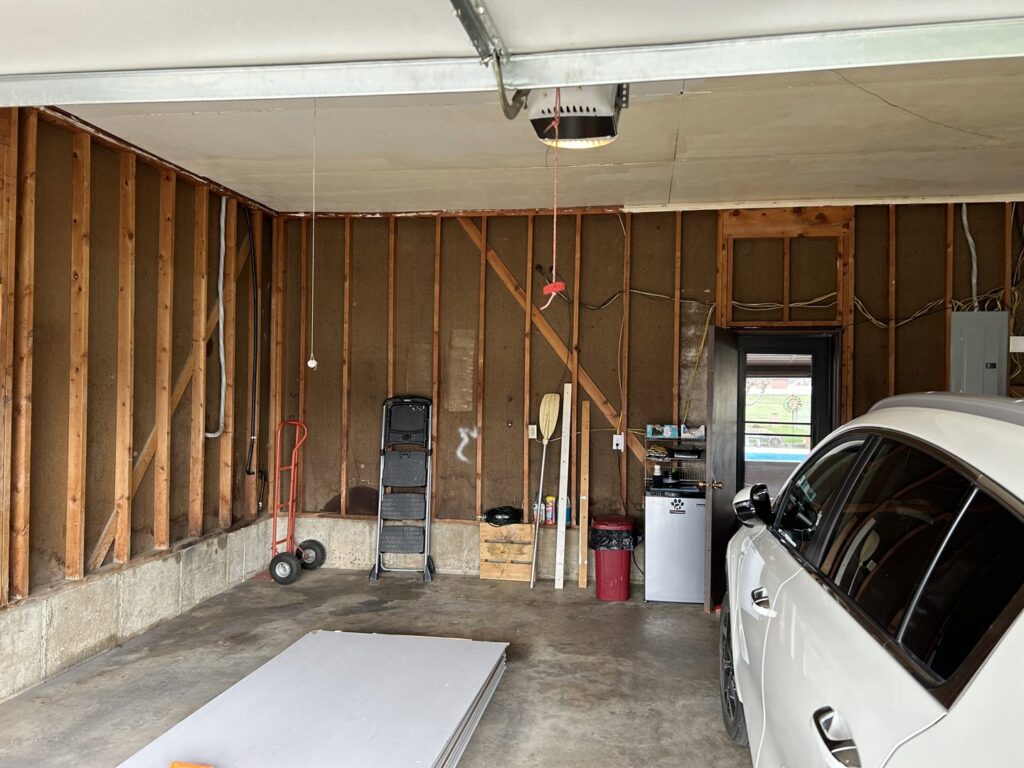 A garage interior with exposed studs and insulation, indicating ongoing renovation by Rockin & Rollin Handyman Services in North Ogden, UT.