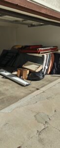 A garage entrance filled with mattresses, boxes, and various junk items for New Haul Junk Removal in Los Angeles, CA.