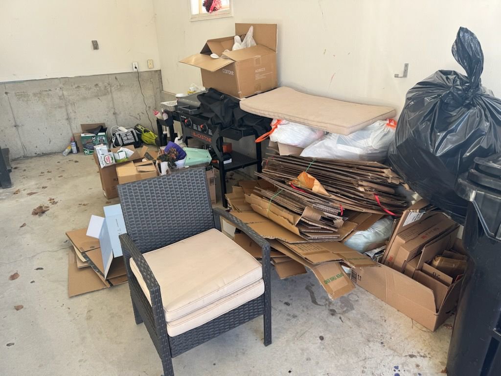 A garage filled with a large pile of cardboard boxes, a chair, and other items ready for junk removal by Rizzo Junk Removal in Nashua, NH.