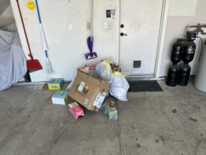 A pile of cardboard boxes and trash bags in a garage, indicating junk removal services by Handyman Service's in North Las Vegas, NV.