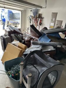 A garage filled with various junk items being removed by 1-800-GOT-JUNK? in Bronx, NY, with a truck outside