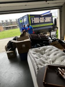 1-800-GOT-JUNK? crew members removing a mattress, boxes, and furniture from a garage in Bronx, NY
