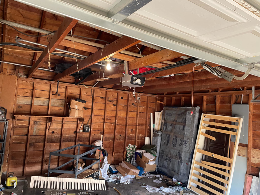 A cluttered garage packed with old furniture, boxes, and various junk items before removal by 575 Junk Removal in Clovis, NM.