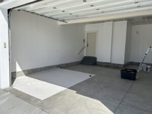 A garage painting project in progress with freshly painted walls and drop cloths by Rockin & Rollin Handyman Services in North Ogden, UT.