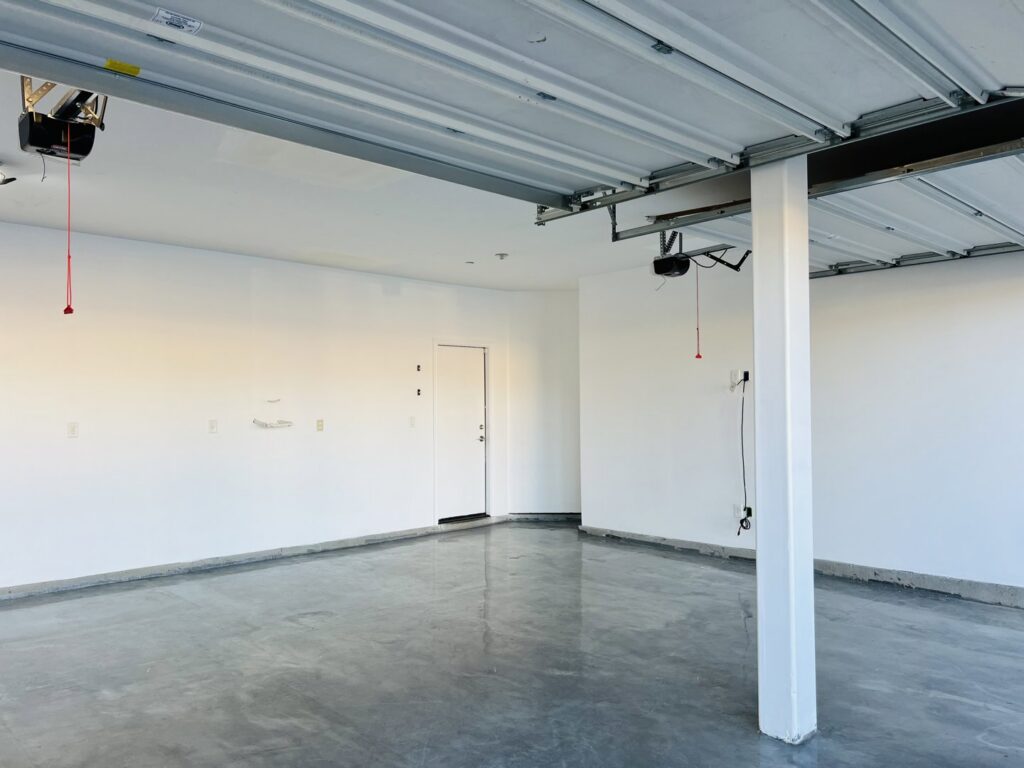 A newly renovated garage with white walls and a grey epoxy floor by Peak Handyman Services in Las Vegas, NV.