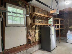 A garage interior undergoing renovation with exposed studs and wooden shelves by Castle Drywall & Plaster in Chesapeake, VA.