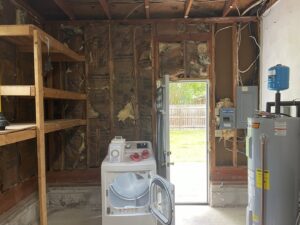 A garage interior undergoing renovation with exposed studs and a water heater by Castle Drywall & Plaster in Chesapeake, VA.
