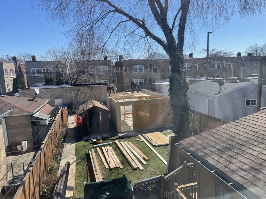 Workers on the roof of a garage under construction, viewed from above, by A-Windy City Garages & Doors in Chicago, IL.