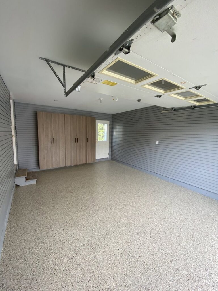 Garage interior with installed slatwall panels and light wood cabinets by PremierGarage of Baltimore in Baltimore, MD.