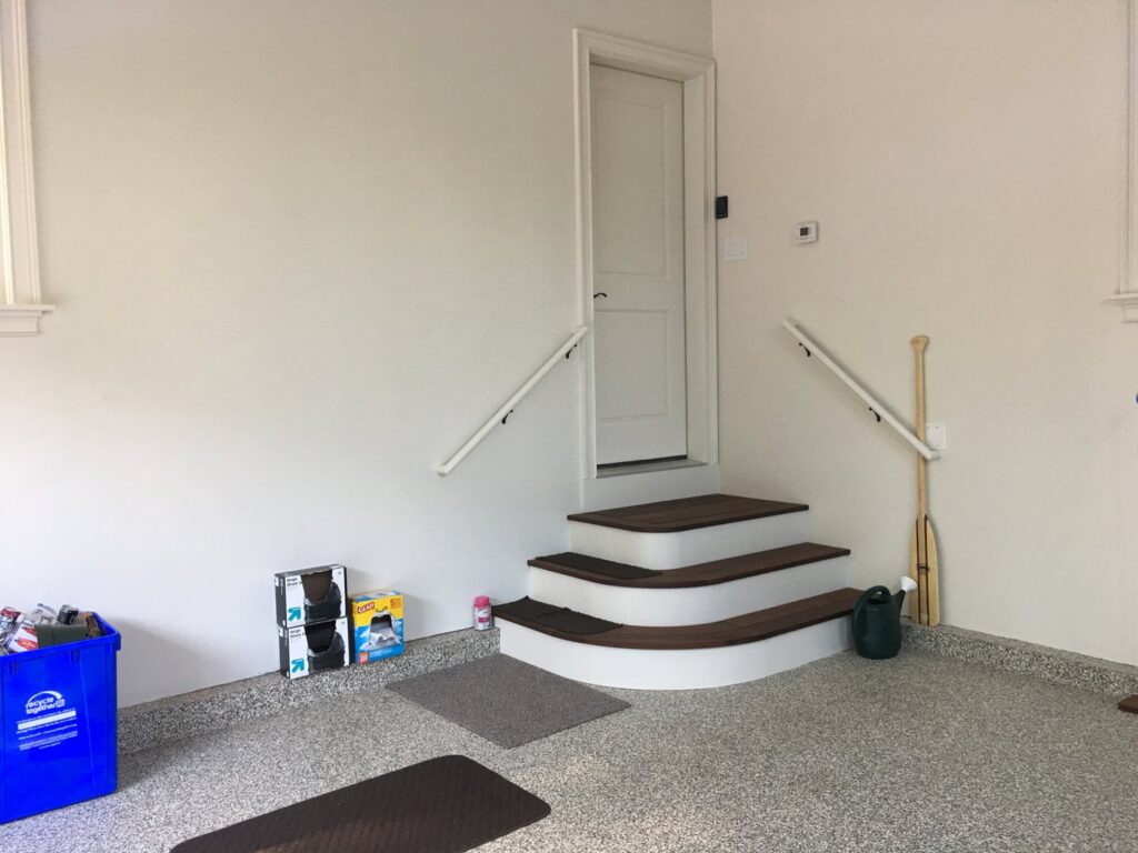 Newly installed curved stairs and handrails in a garage, completed by BizMick Construction in Coventry, RI.