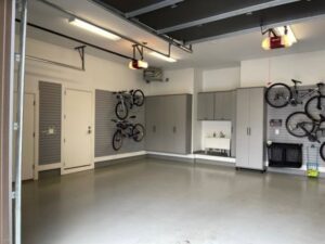 A garage featuring grey storage cabinets, a utility sink, and wall-mounted bike racks installed by Closet Creations Inc. in Sleepy Hollow, NY.