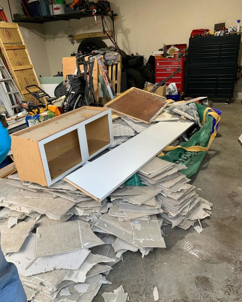 A garage filled with construction debris, old cabinets, and junk, ready for removal by You Call We Haul Junk Removal in Milwaukee, WI.