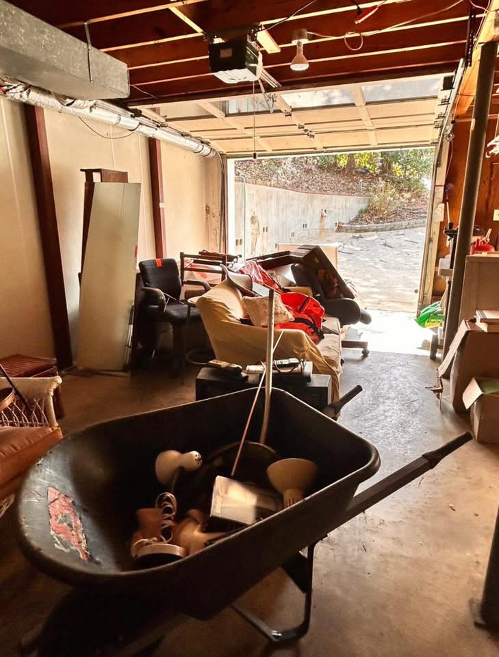 A garage filled with old furniture and debris, including a wheelbarrow, for Marc & Park Junk Removal, LLC in Birmingham, AL.