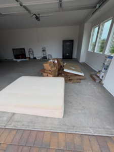 A garage with a mattress and a pile of cardboard boxes, indicating a junk removal job for Tough Guy Junk Removal in Fountain Hills, AZ.