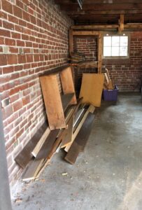 A garage with brick walls and a pile of wooden planks and boards, awaiting junk removal by Goblins Junk Removal in Wheat Ridge, CO.