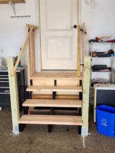 Newly constructed wooden steps with railings leading to a door in a garage, built by Go Joe Handyman in Overland Park, KS.