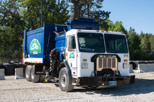 A white and blue garbage collection truck with the Evergreen Disposal logo in Kalispell, MT.